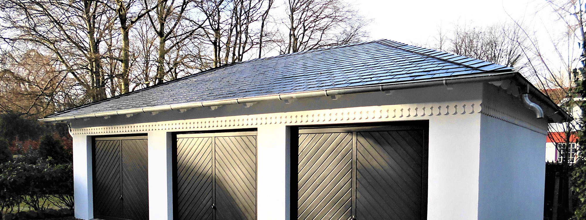 Das Foto zeigt eine individuell geplante Garage mit Walmdach von M.S. Garagenbau, harmonisch in die Umgebung integriert.