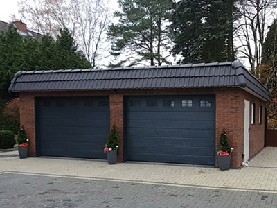 Individuell geplante Walmdach-Garage: Perfekte Harmonie mit der Umgebung. Lassen Sie Ihre Garage von M.S. Garagenbau gestalten und bauen. Auf dem Bild ist eine Walmdach-Garage von M.S. Garagenbau, perfekt an die Architektur angepasst und individuell geplant zu sehen.