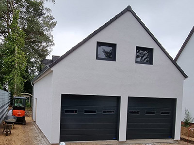 Hier sieht man eine maßgeschneiderte Satteldachgarage von M.S. Garagenbau, klassisch und stilgerecht im zeitlosen Design.