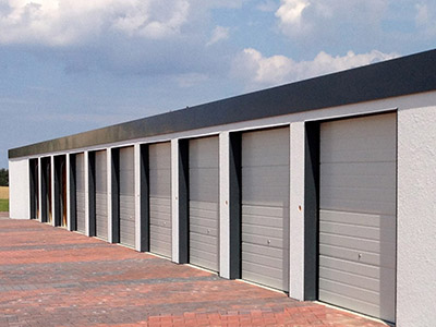 Individuelle Reihengaragen für mehrere Fahrzeuge. Lassen Sie Ihre Reihengaragen von M.S. Garagenbau GmbH maßgeschneidert planen und bauen. Hier ist eine große Reihengarage für 10 Fahrzeuge mit 10 Toren abgebildet, wie man sie aus Wohngebieten mit Doppelhausreihenhälften kennt. Das simple Design überzeugt mit funktionellen Rolltoren.