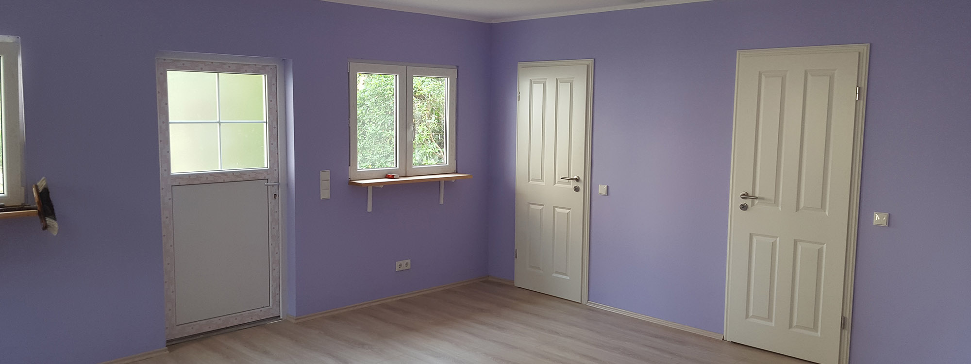 Auf dem Bild ist ein lichtdurchfluteter Innenraum einer Garage in lila Farbe gestrichen zu sehen. Die Garage dient als Kellerersatz und wurde individuell gestaltet.